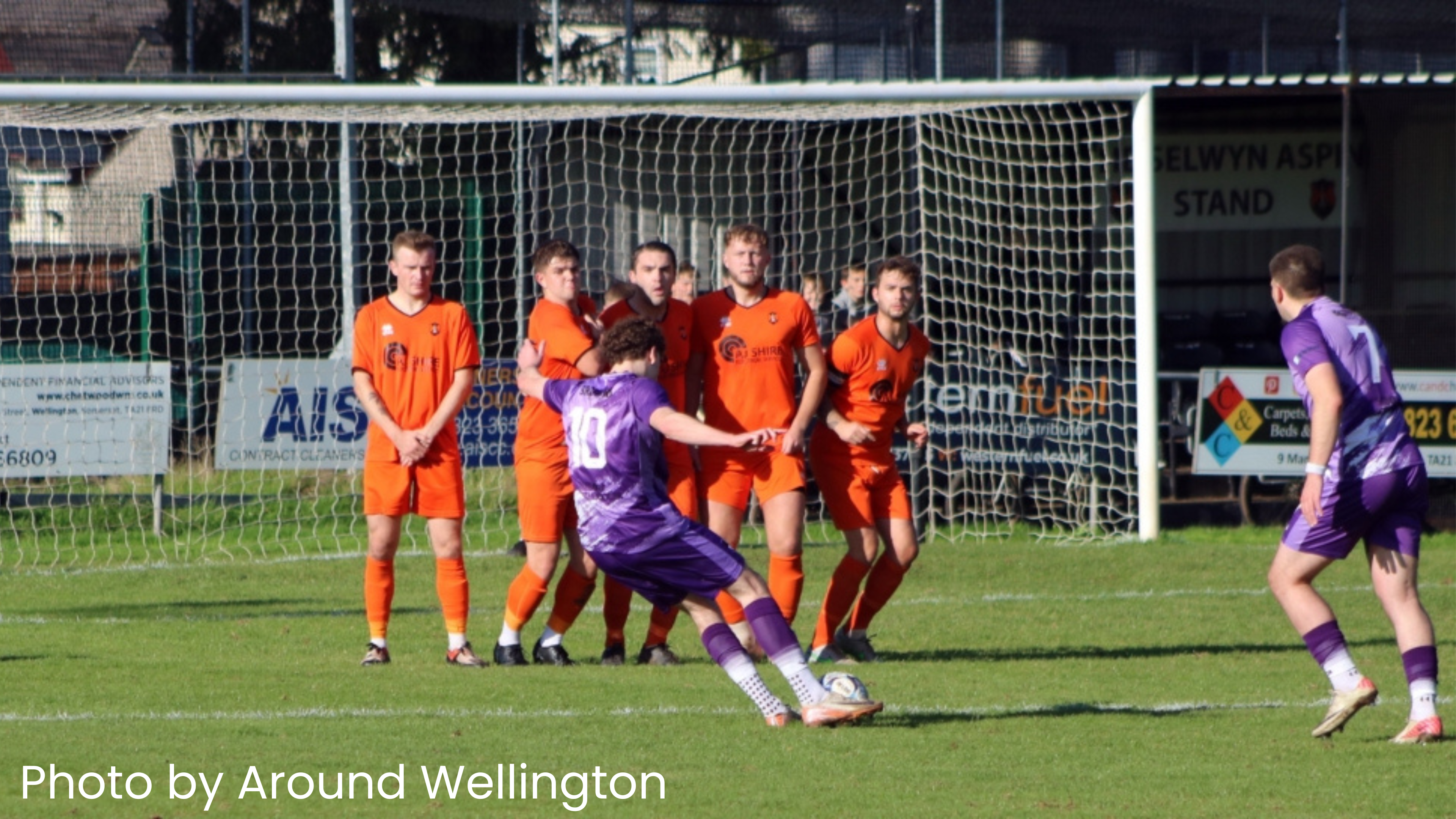Photo by Around Wellington. A group of men playing football. A player takes a penalty shot.