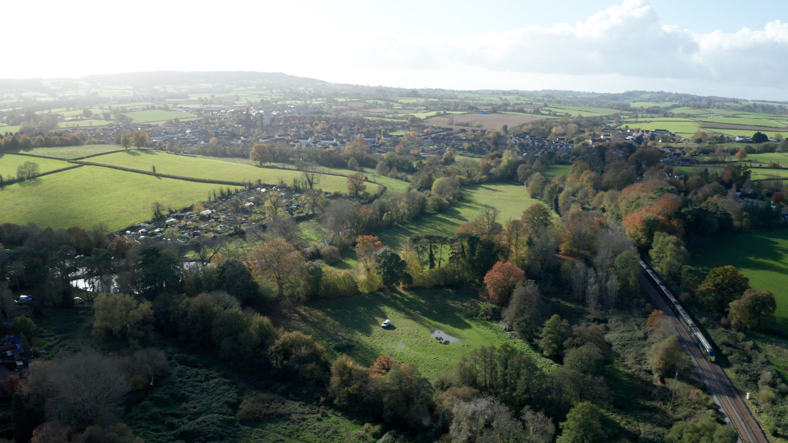 An aerial view of fields and woodland with the village of Rockwell Green and the Blackdown Hills in the background.